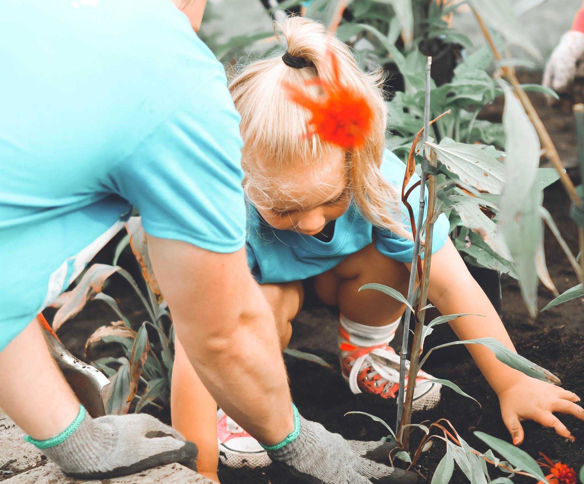 A woman and child are planting flowers in a garden