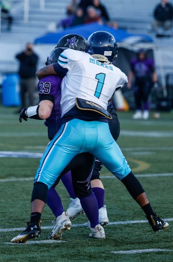 A football player in red uniform running with the ball, wearing a helmet.