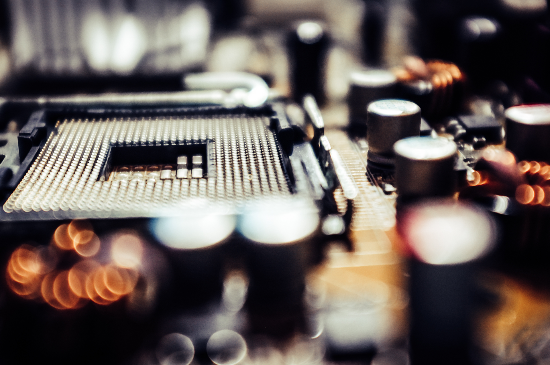 Close-up of a computer motherboard socket, surrounded by electronic components, slightly out of focus.