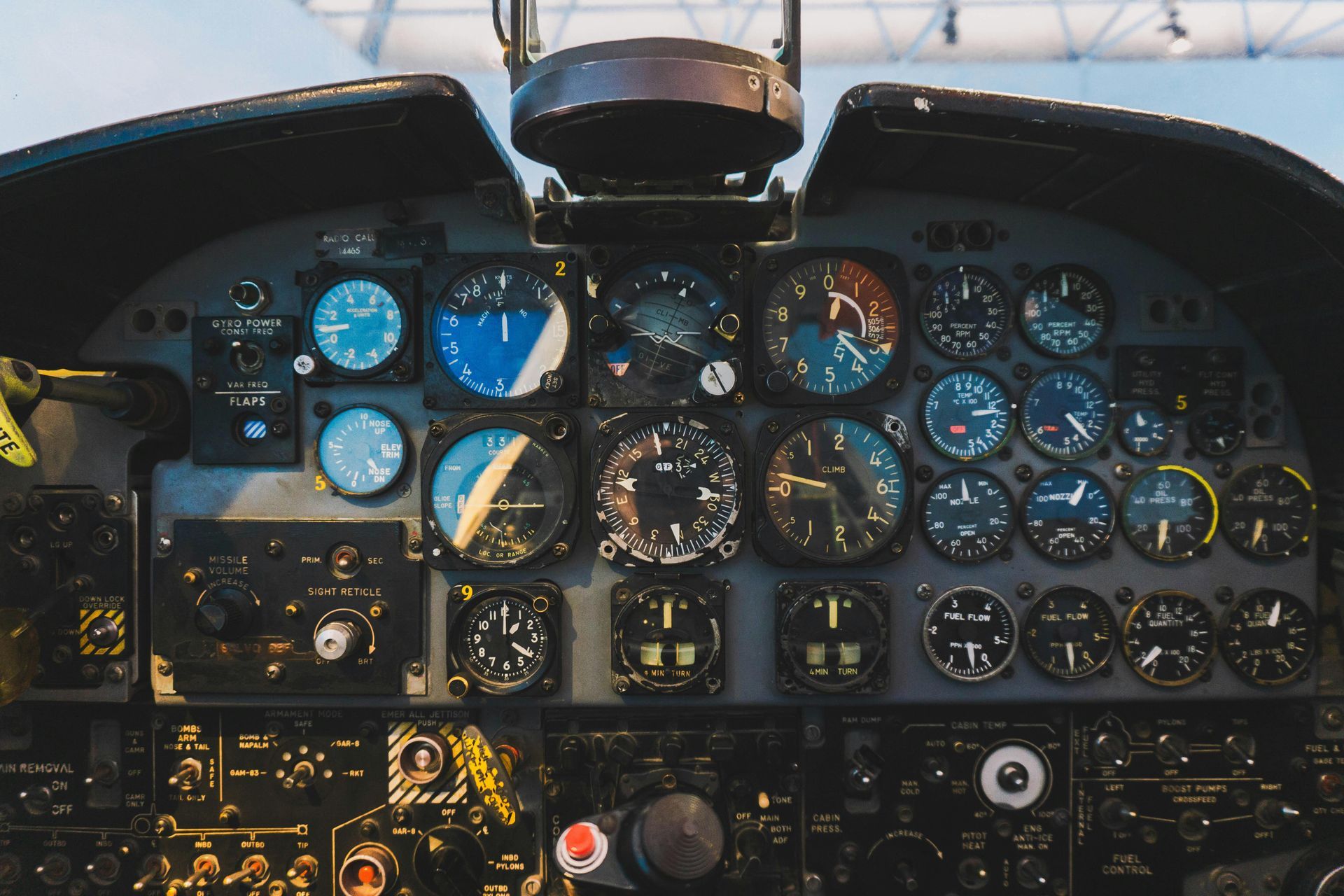 Close-up of an aircraft cockpit filled with various gauges and control panels, primarily in shades of black, blue, and white.
