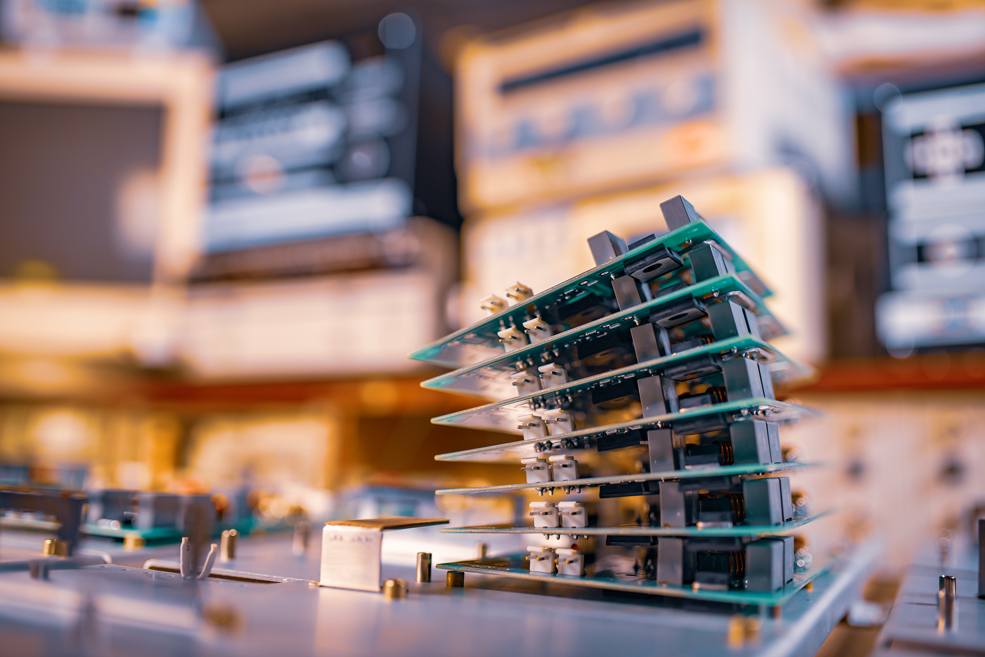 Stack of circuit boards in a lab setting; green and black boards with electronic components.