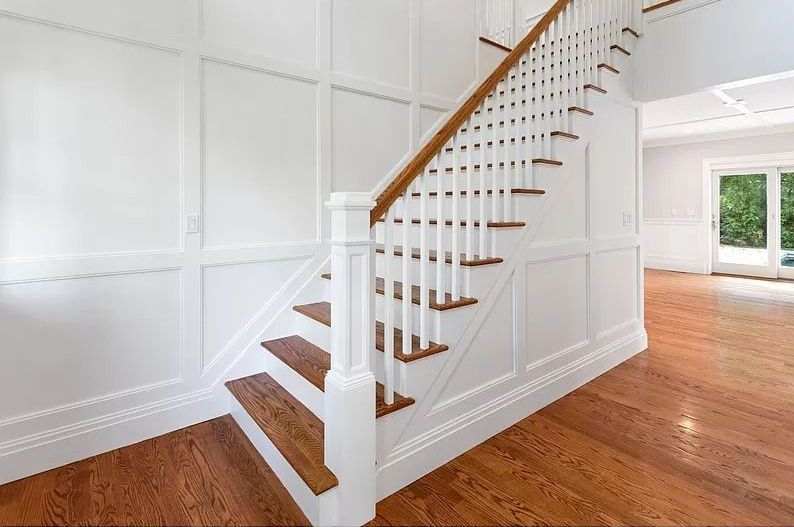 A staircase with white railings and wooden steps in an empty house.