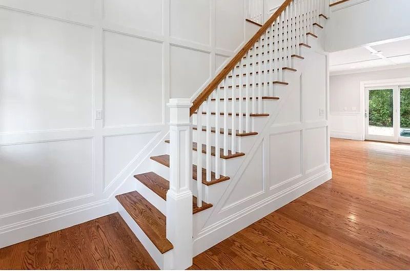 A staircase with white railings and wooden steps in an empty house.