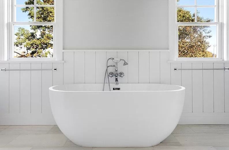 A white bathtub in a bathroom next to a window.