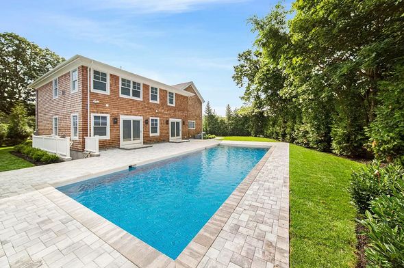 A large brick house with a large swimming pool in front of it.