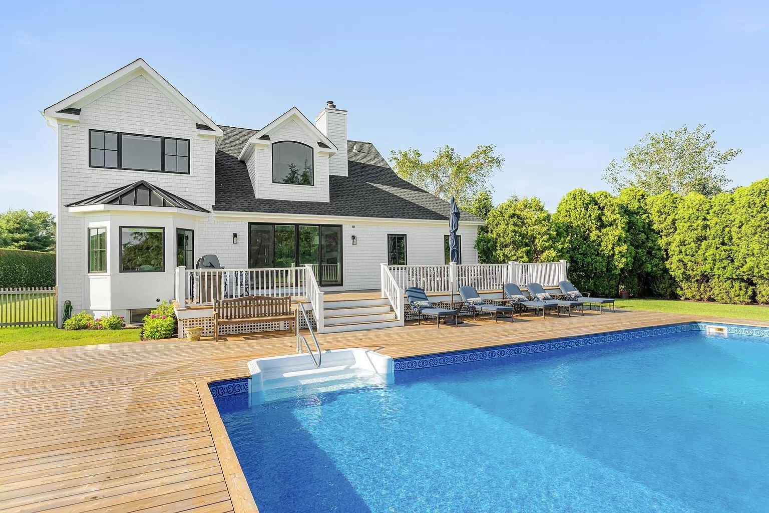 A large white house with a large swimming pool in front of it.