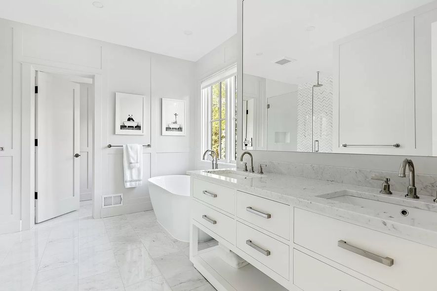 A bathroom with two sinks , a tub , and a mirror.