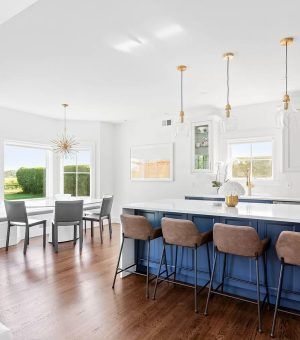 A kitchen with a blue island , white counter tops , and wooden floors.