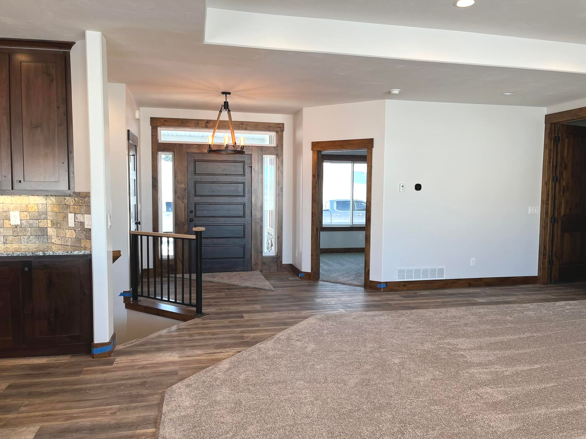 Interior view of a home's entryway with a dark door, hardwood floors, and carpet.