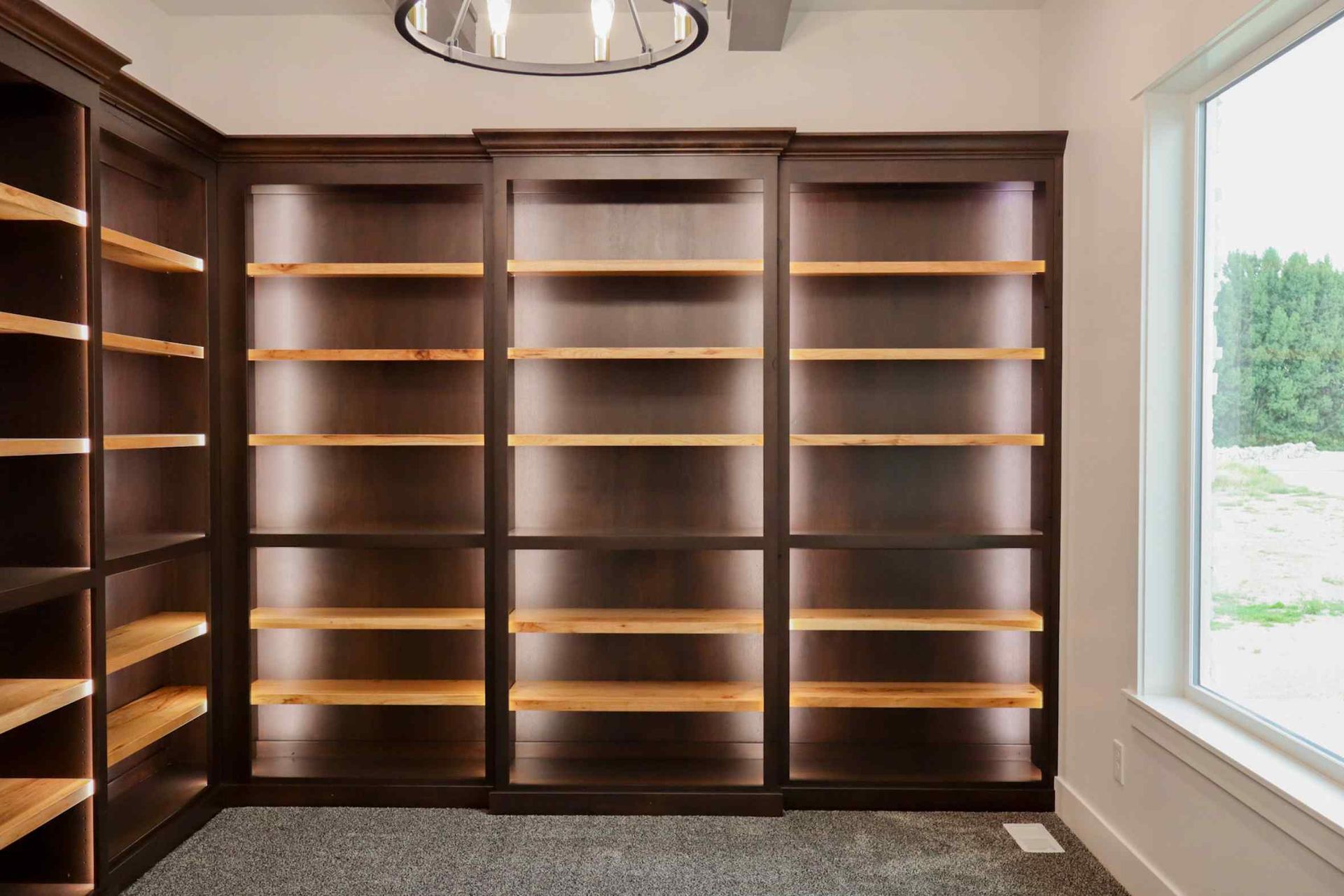 Dining room with wooden table, six chairs, large windows, and a chandelier.
