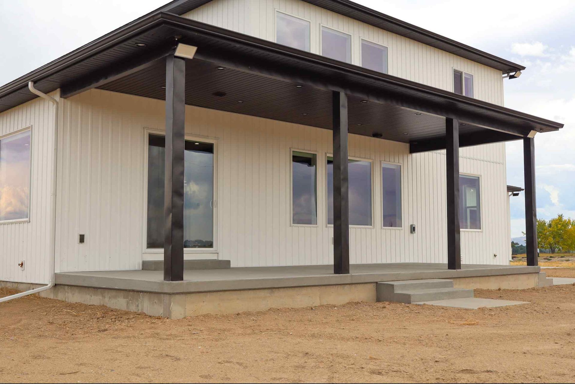 Living room with kitchen in the background. Light wood cabinets, blue walls, a brown couch with pillows, and a dining area.