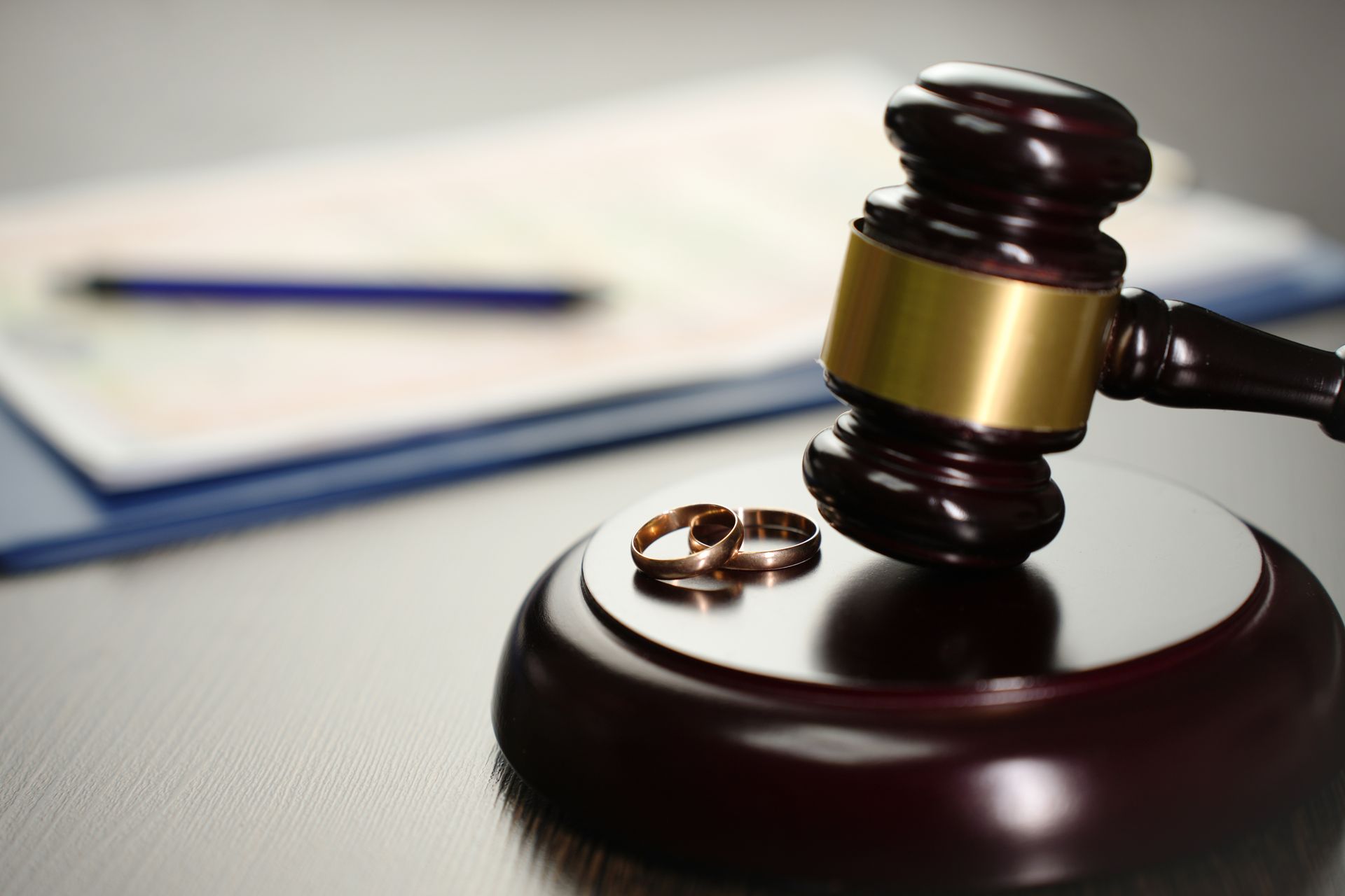 Wedding rings beside a gavel on a sound block; legal documents in the background.