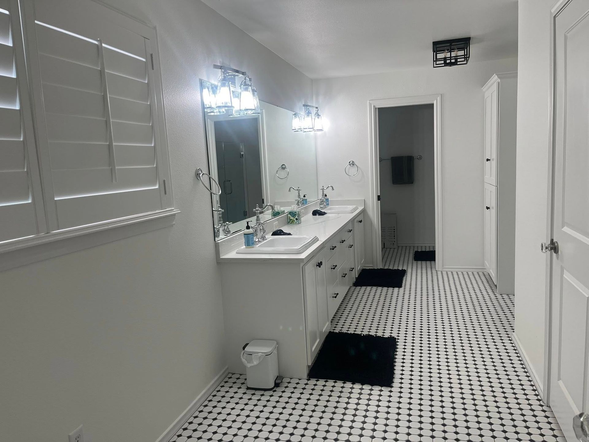 Bathroom with a white vanity, black and white tiled floor, and a closed door.