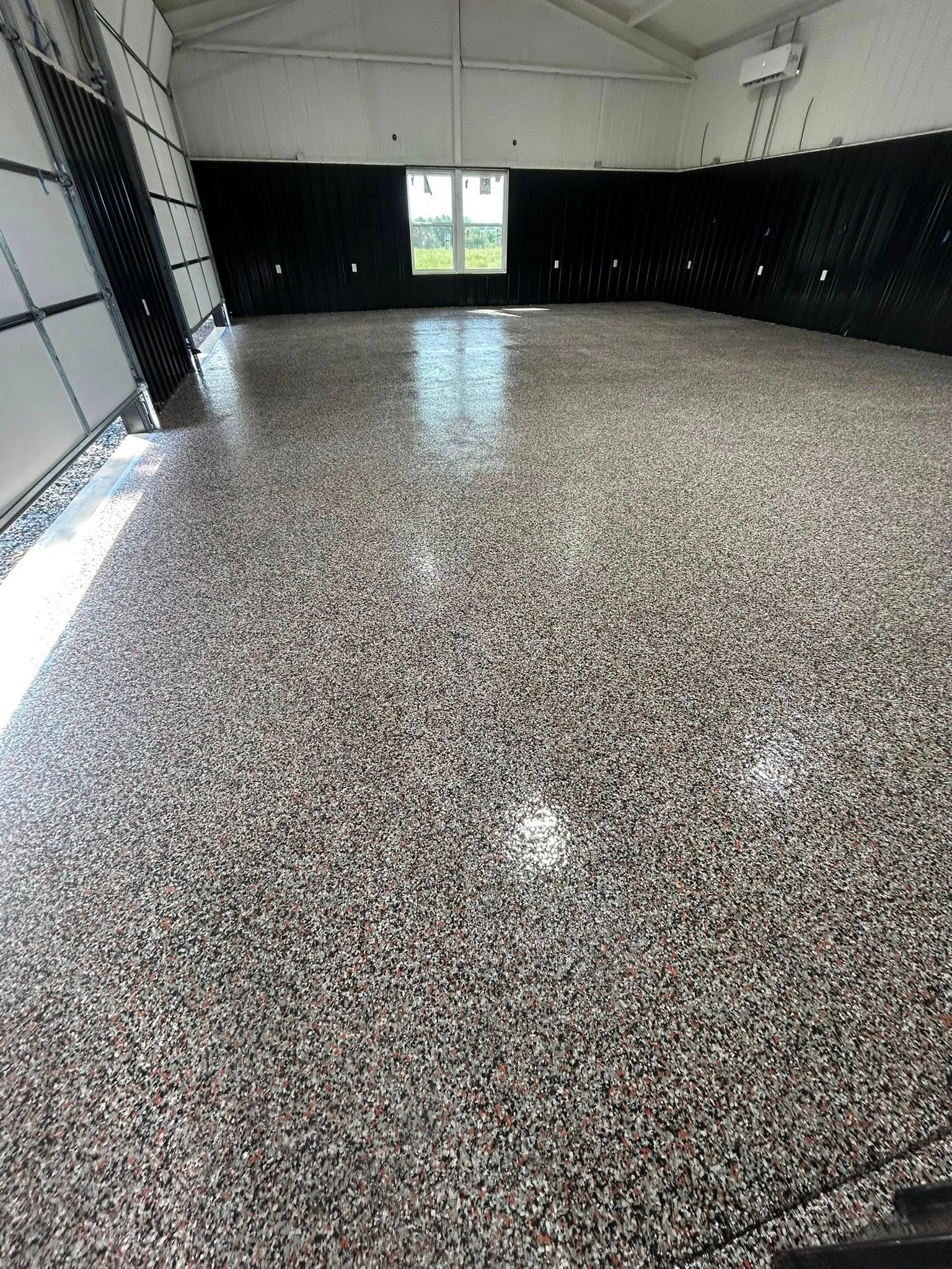 Epoxy-coated floor in a bright warehouse space with a window and black walls.