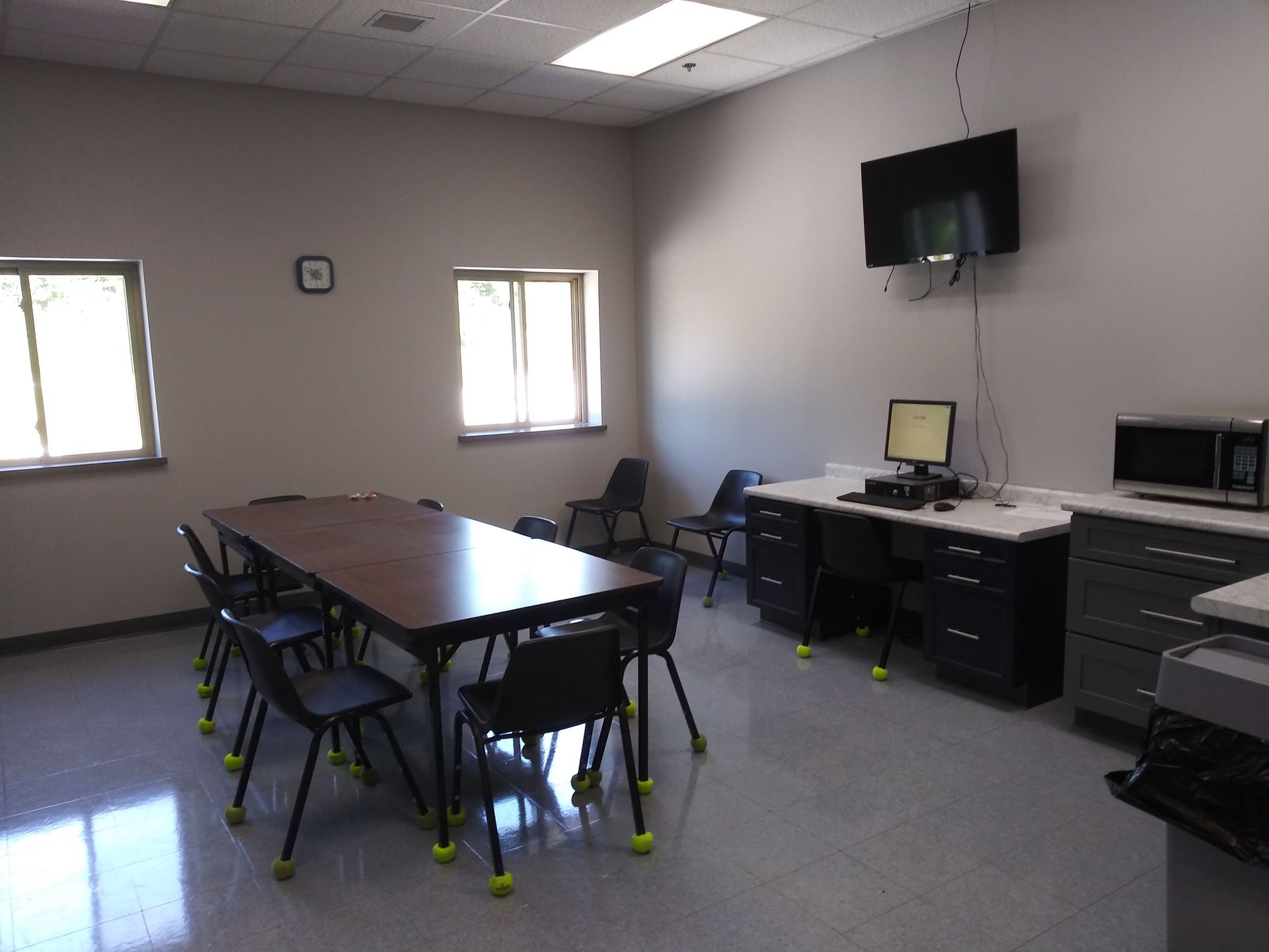 A room with a table and chairs and a computer on the wall