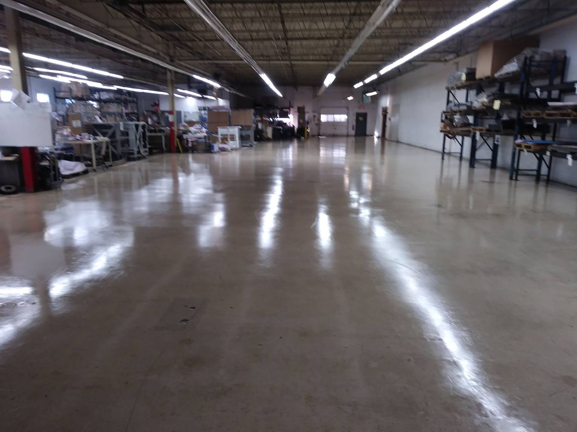 A large warehouse with a shiny floor and lots of shelves.