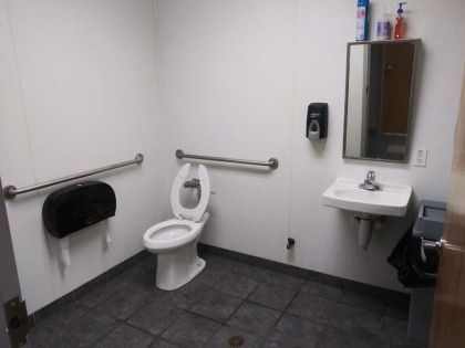 A bathroom with a toilet , sink and mirror.