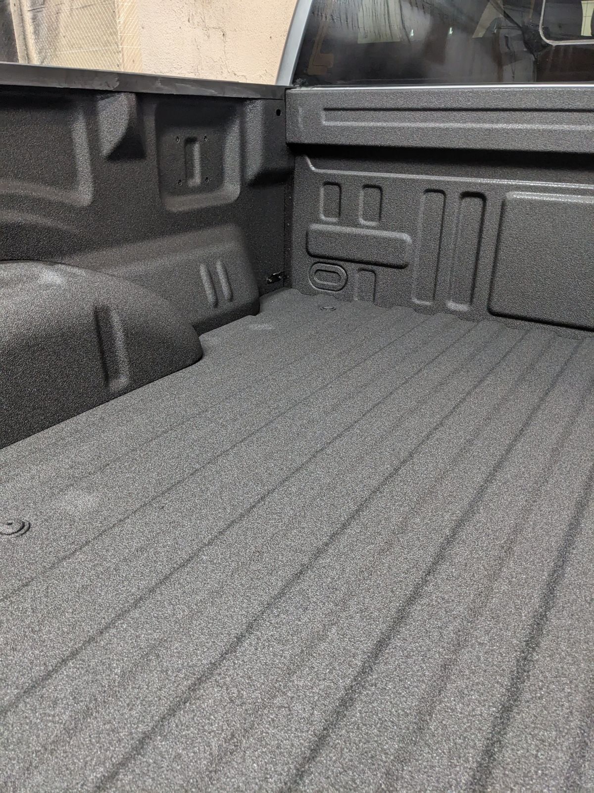 Truck bed with a textured, gray protective coating.