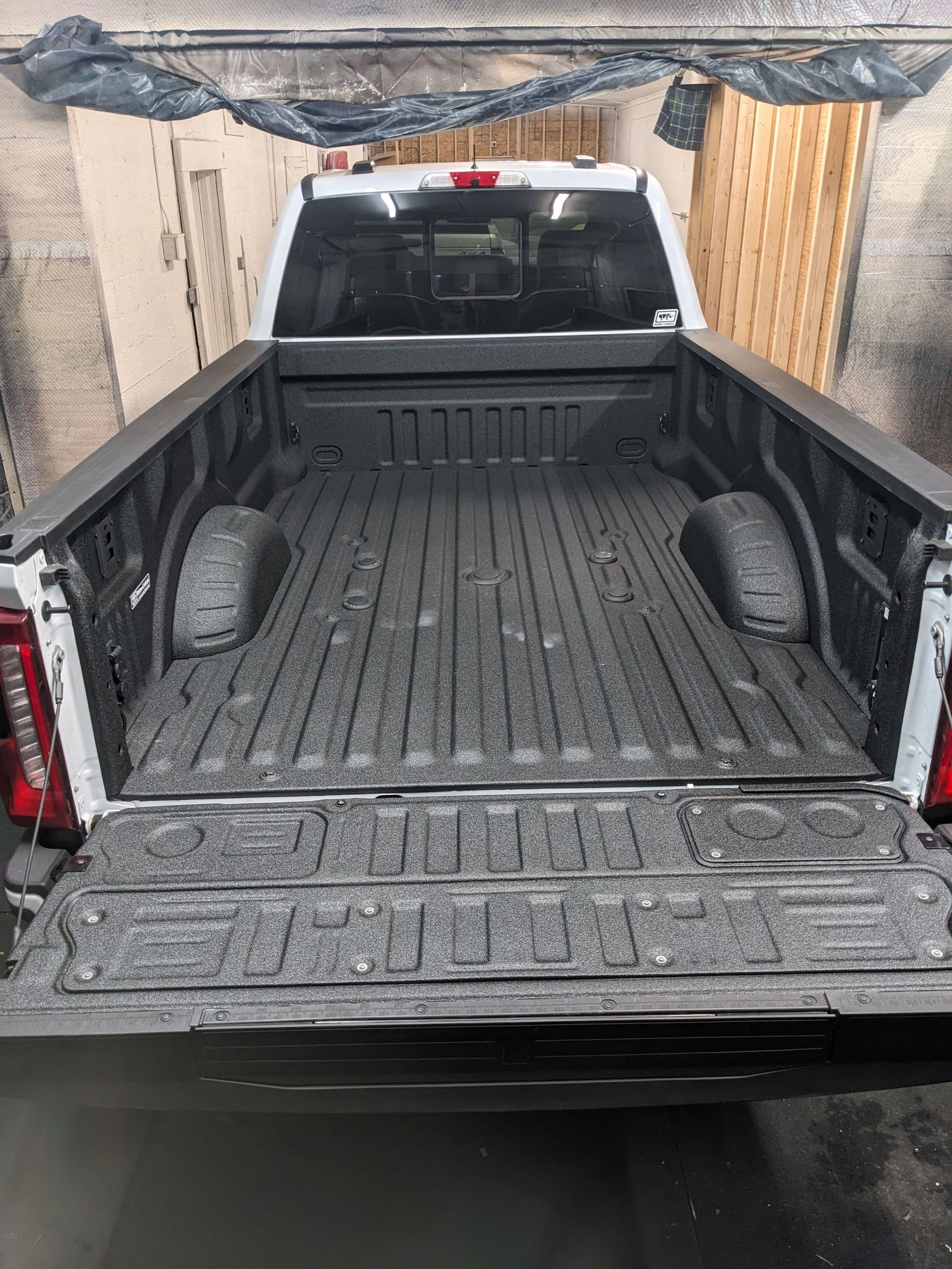 White pickup truck bed with a textured black coating, angled rear view.