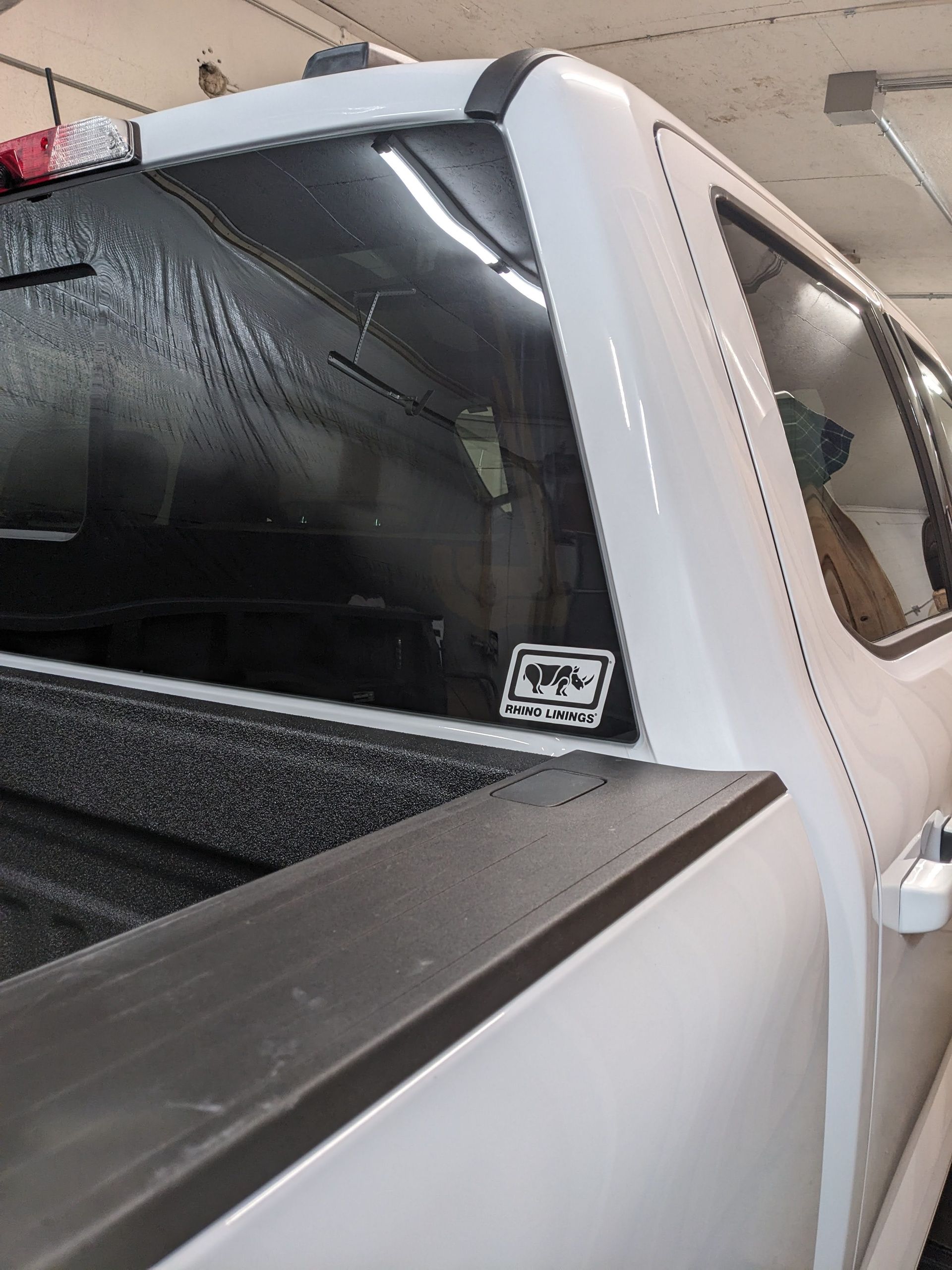 White pickup truck's back with a sticker on the window, bed, and side window visible.