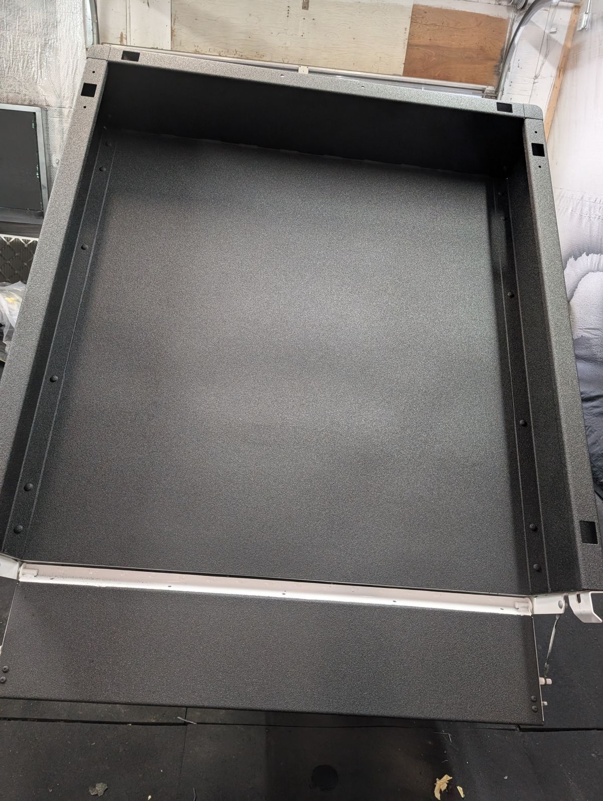 Black, textured metal tray with a raised edge. Top-down view.