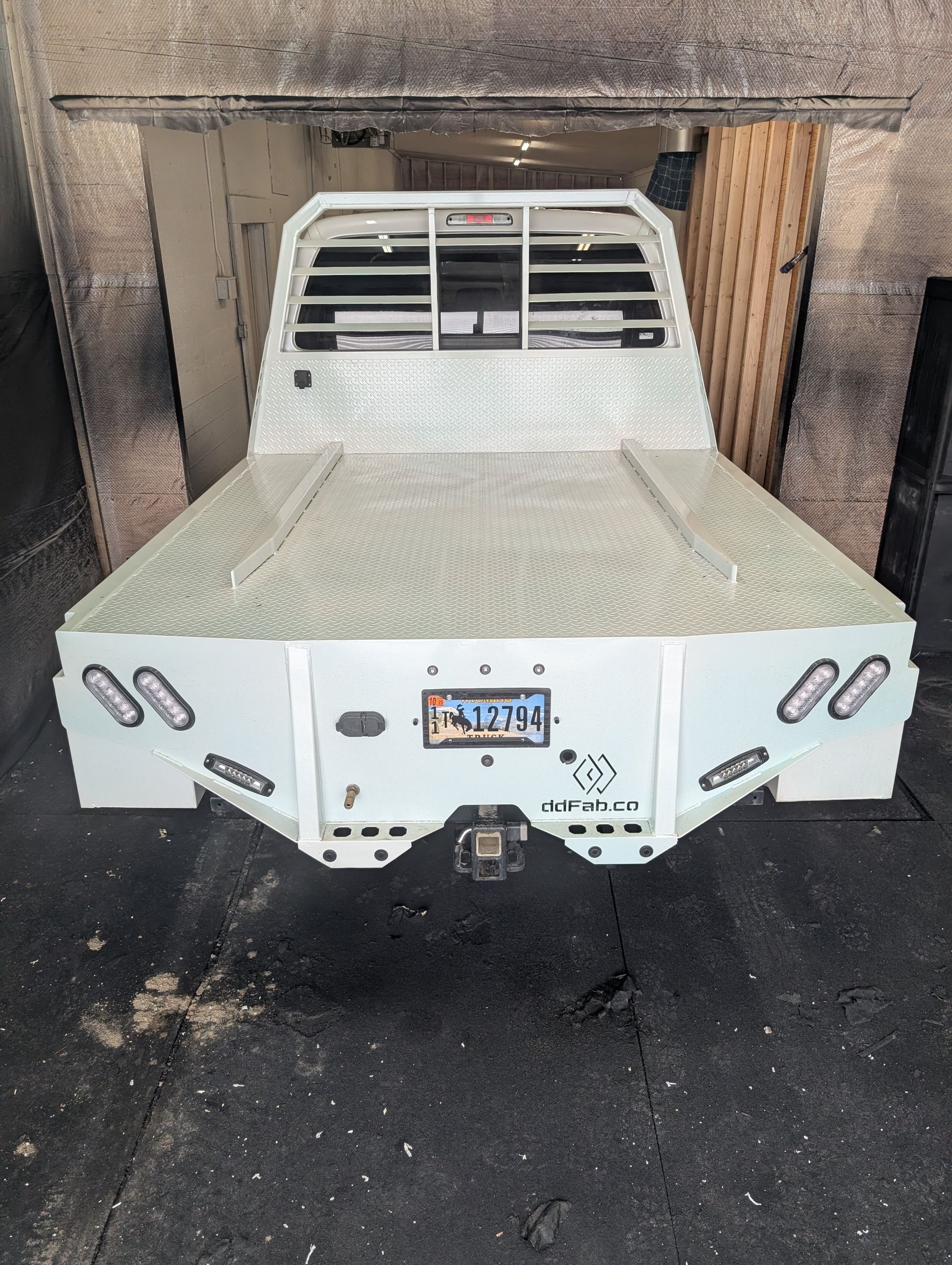 White truck bed with diamond plate, lights, and a license plate.