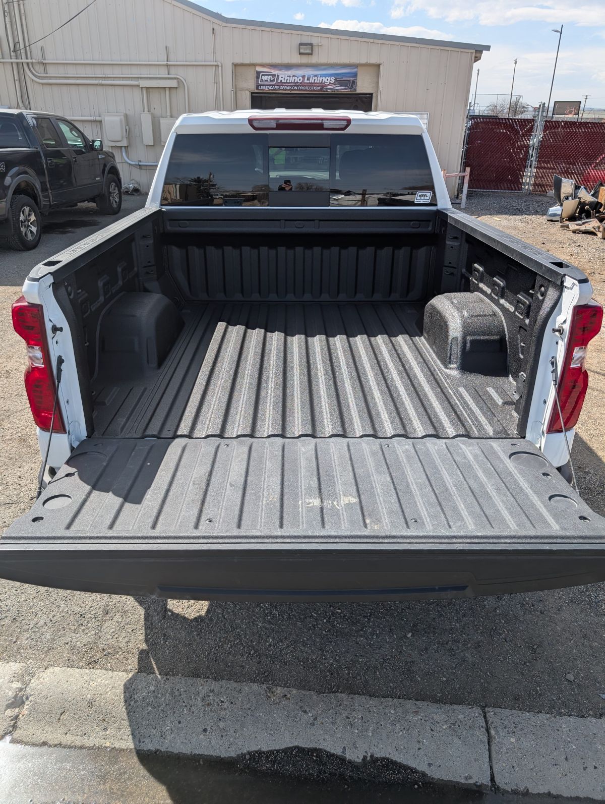 White pickup truck bed with open tailgate and bedliner.