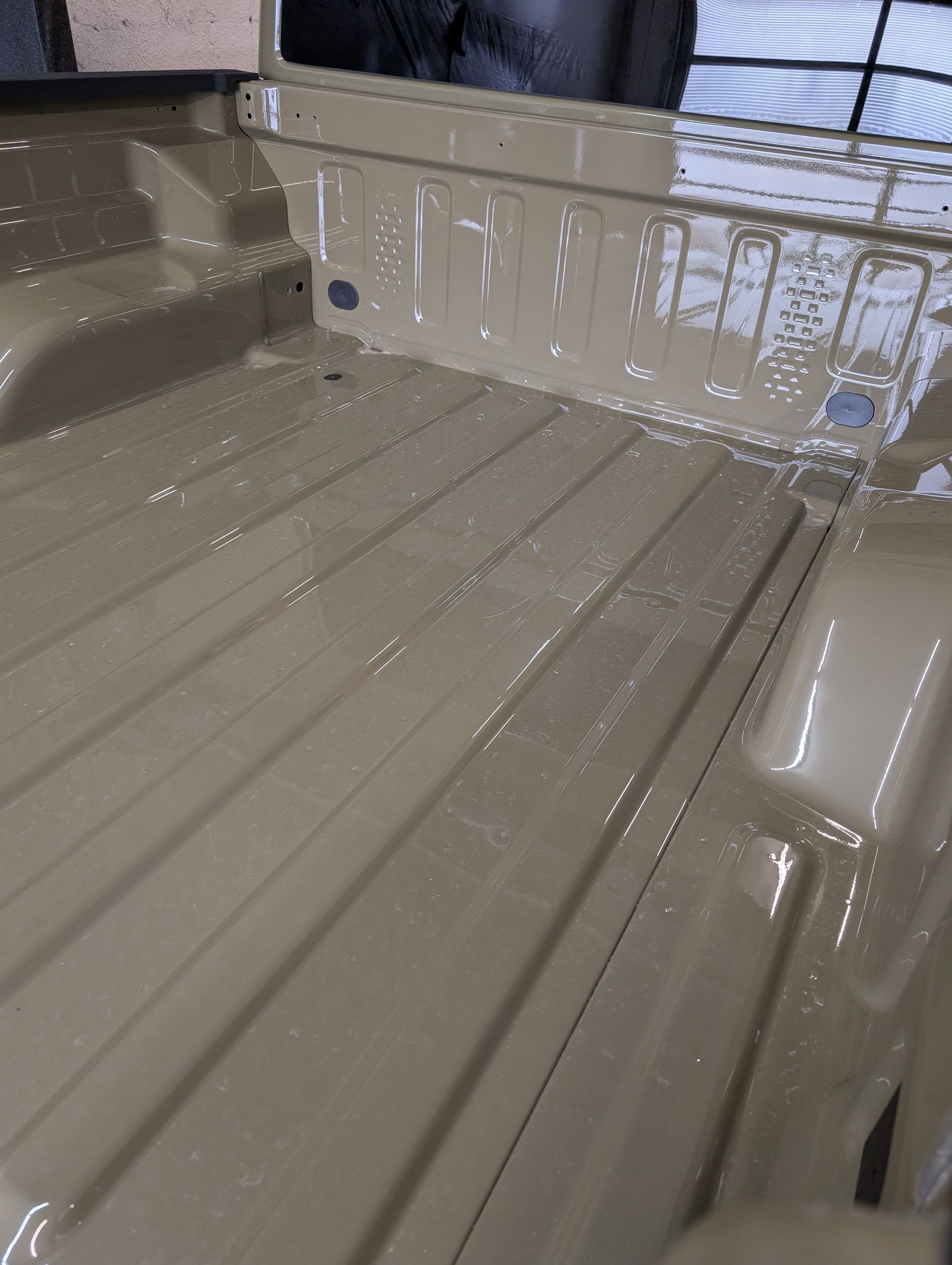 Tan truck bed with a glossy finish, likely freshly coated.