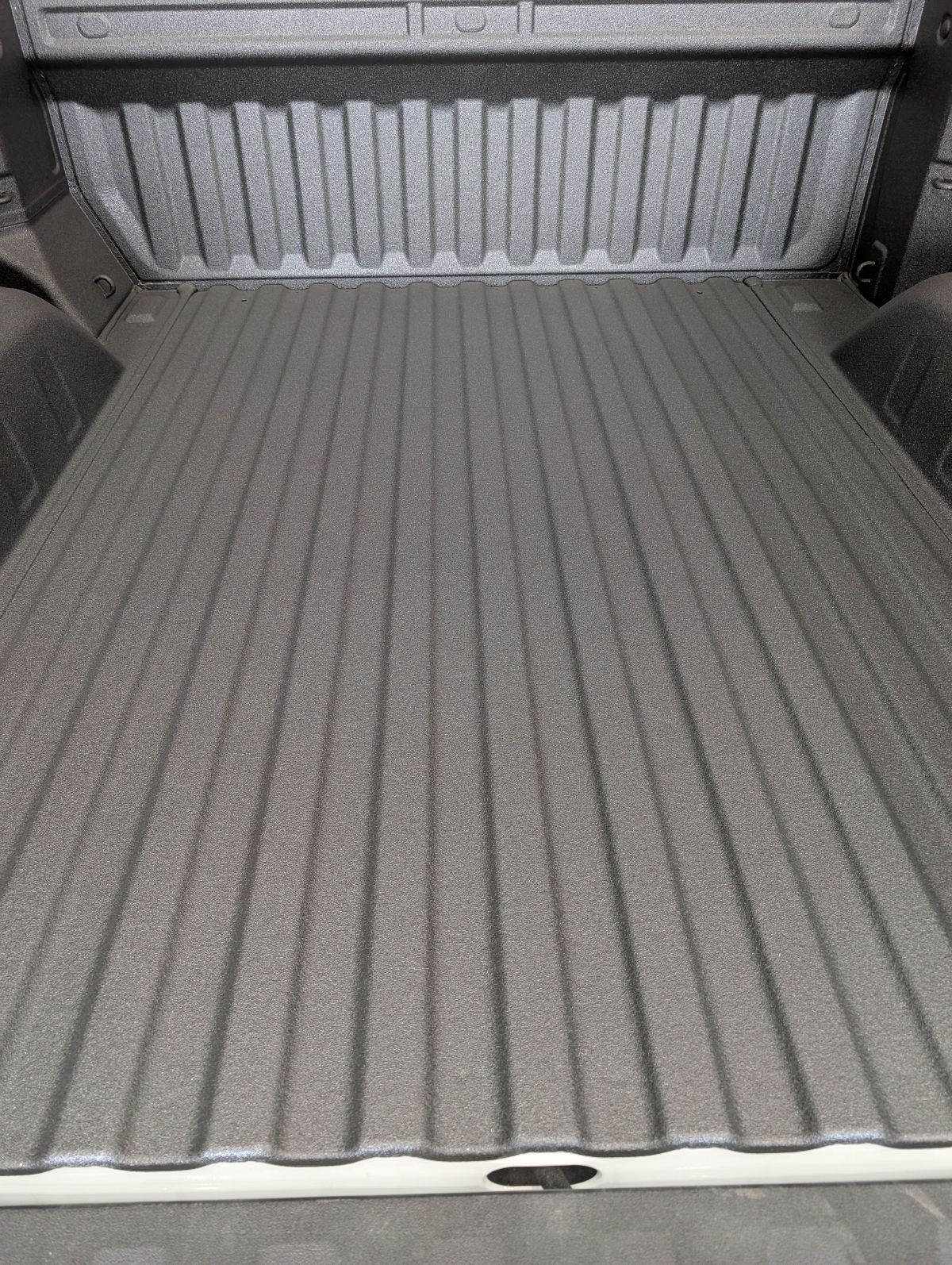 Bed of a gray truck with a textured coating.
