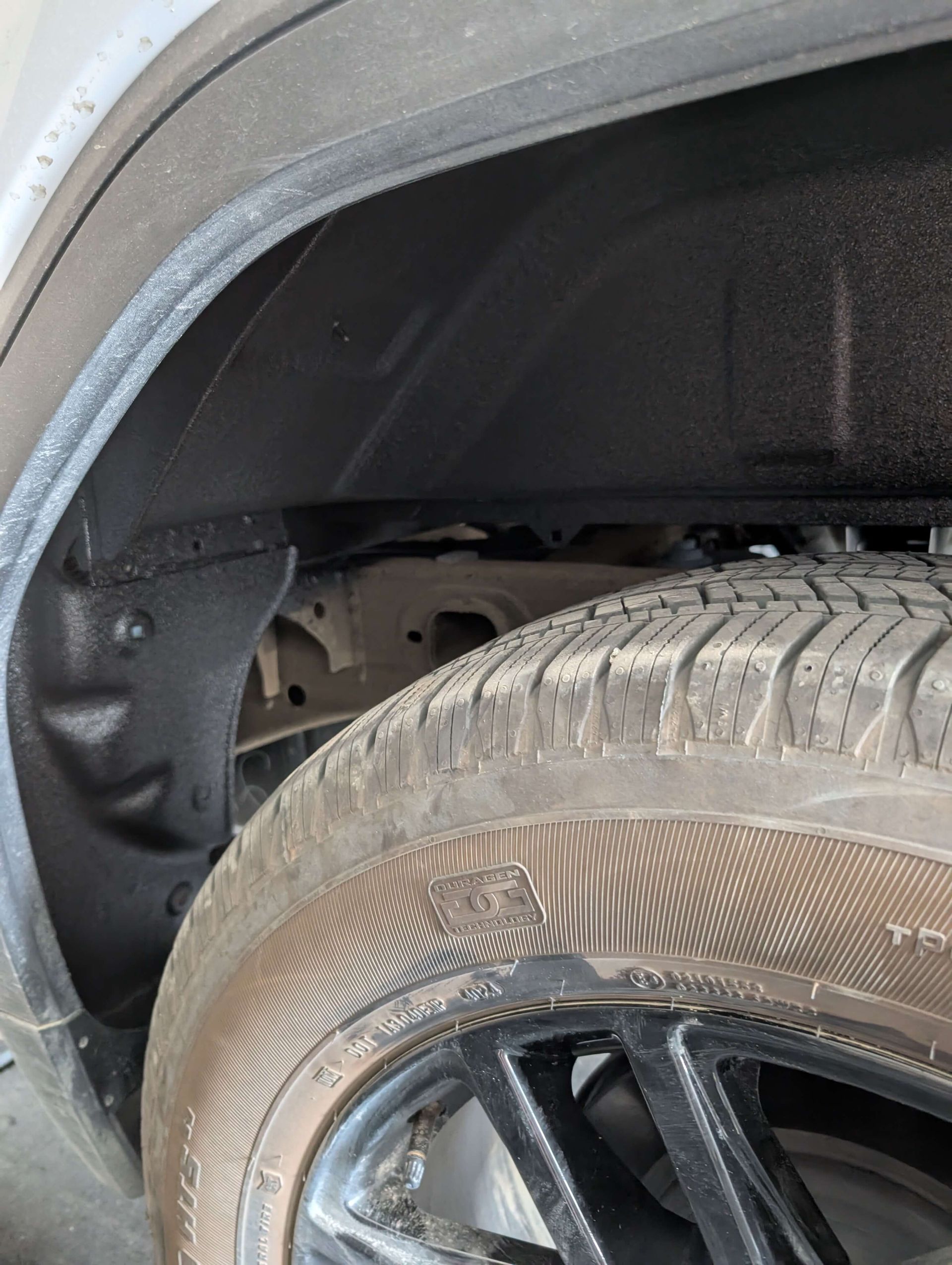Black tire and wheel well of a car, coated in a black protective spray.