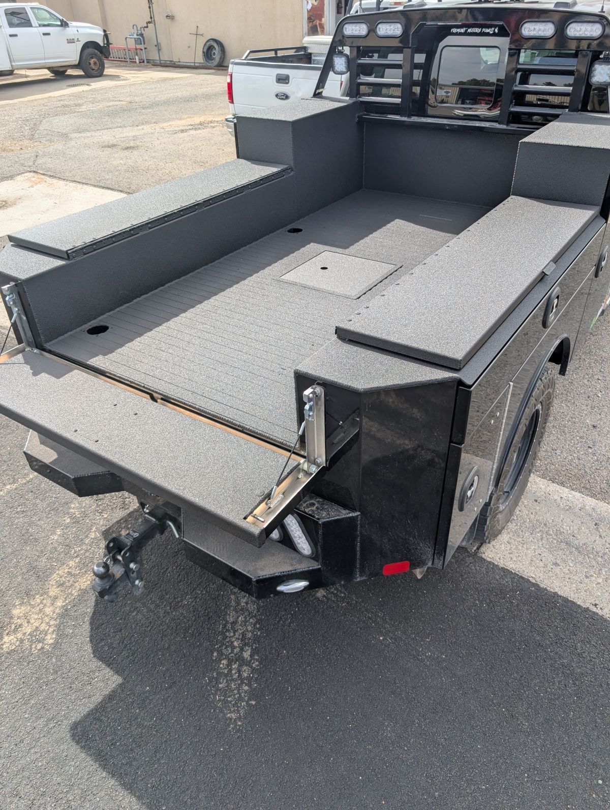 Black flatbed truck with textured surface, in an outdoor setting.