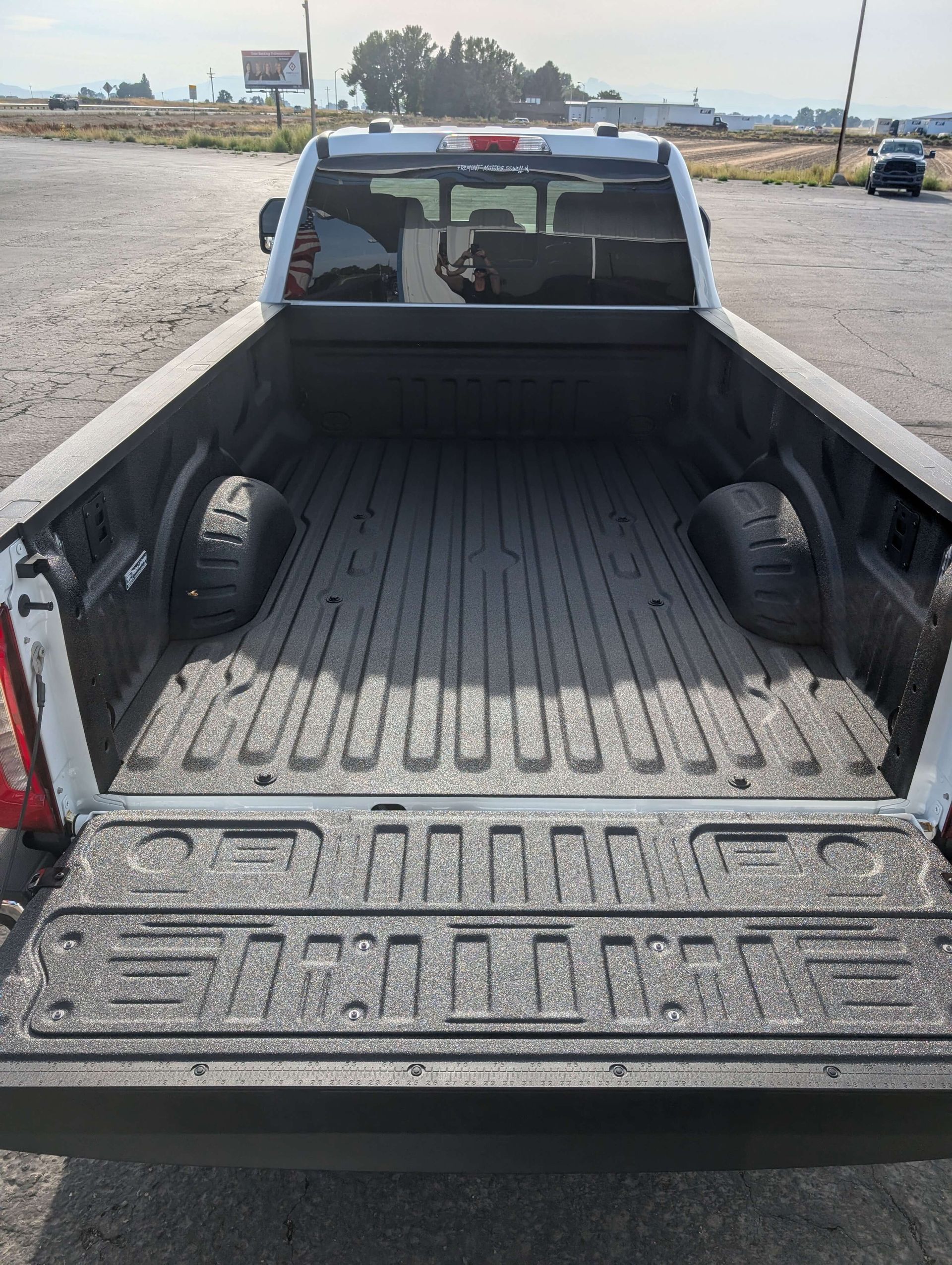 White pickup truck bed with black textured liner, tailgate down, outdoors.