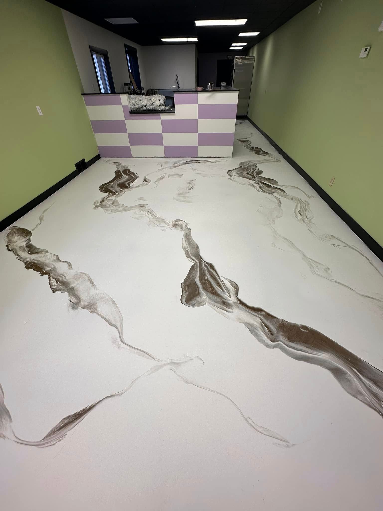 White and brown patterned floor in an empty room, a counter with purple and white squares, green walls.