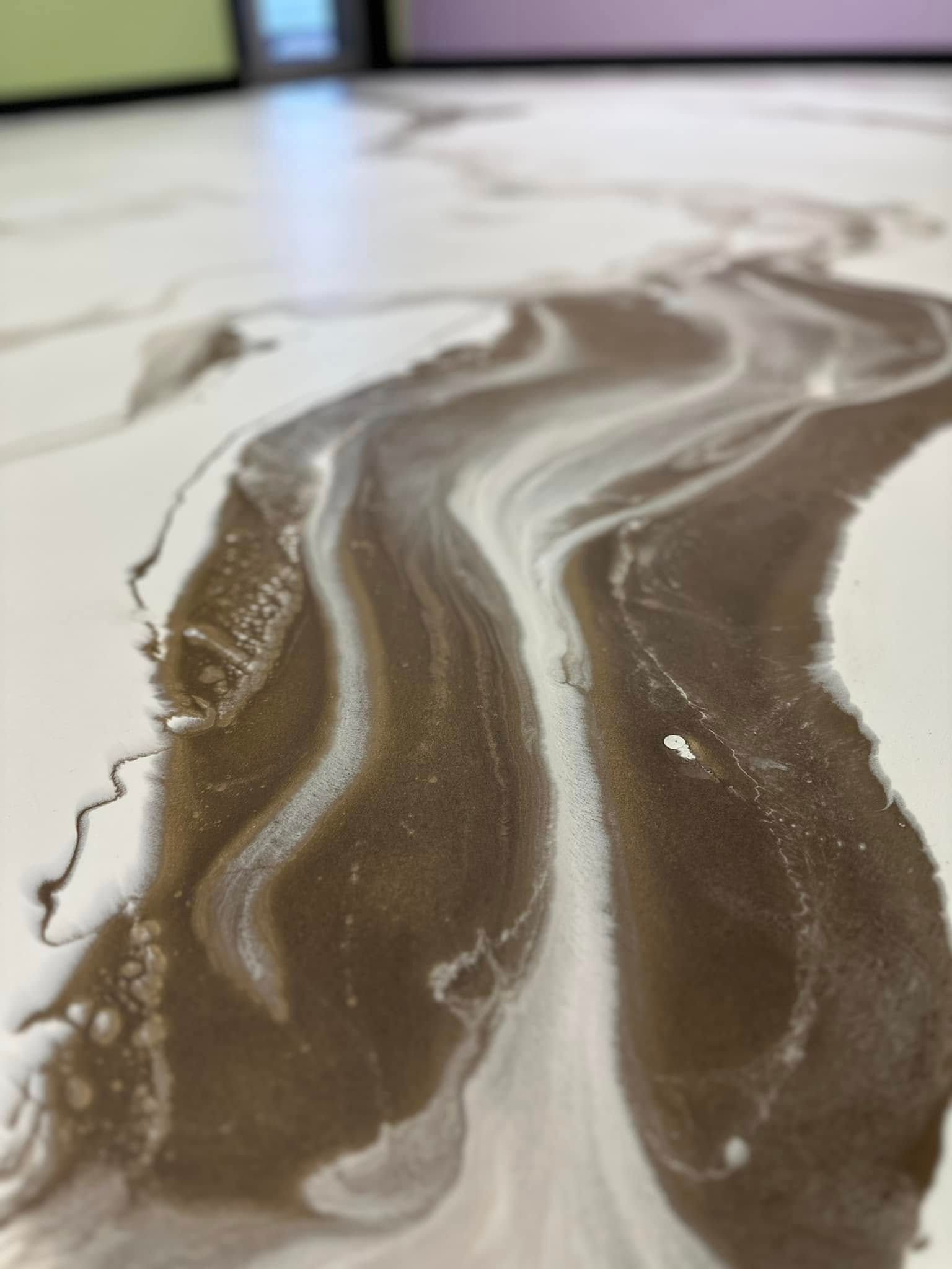 Close-up of a floor with brown and white flowing, swirling patterns.