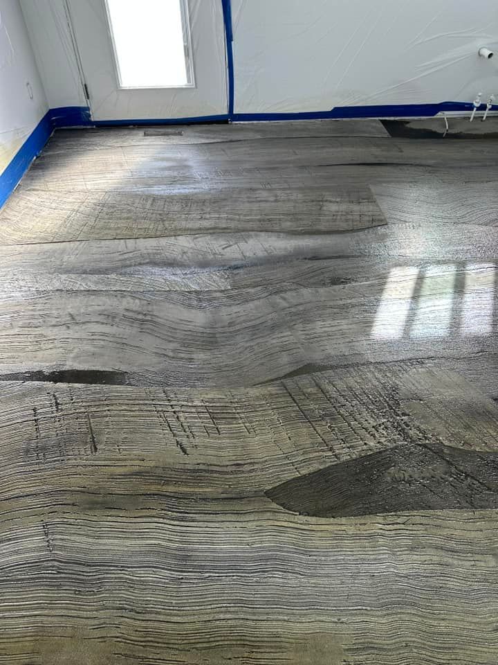 Wood-look flooring, with visible wood grain and distressed texture, reflects light in a room with a window.