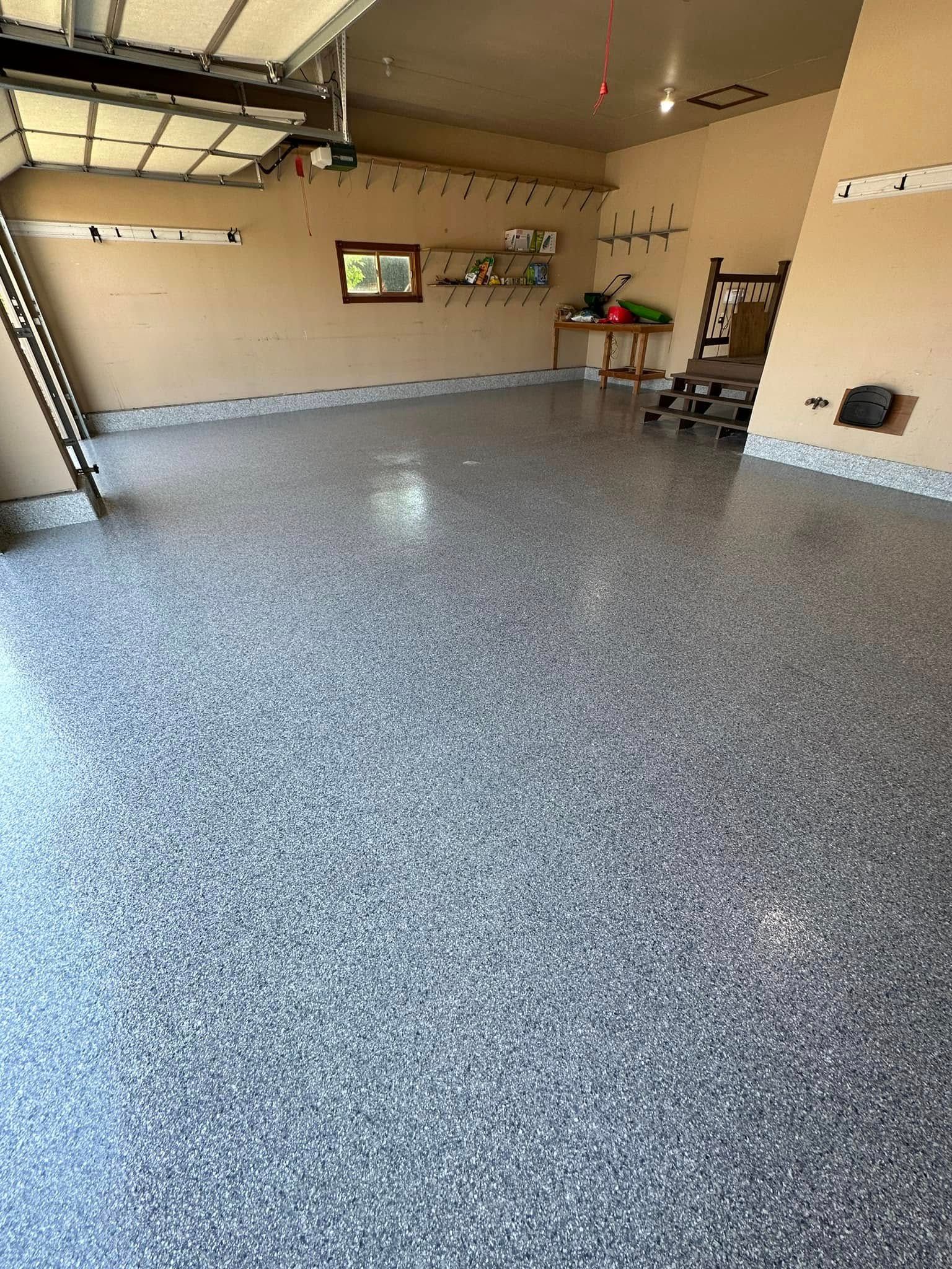 Garage with epoxy floor, a ladder, and some shelving. The floor is speckled with gray and white chips.