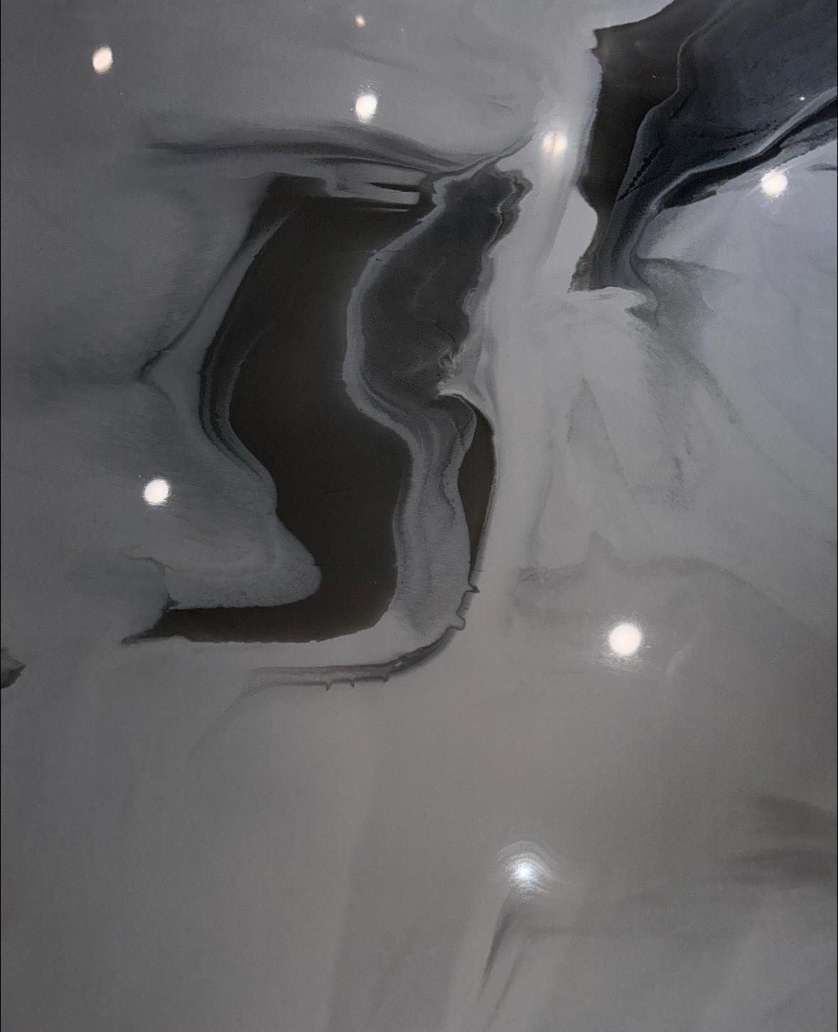 Swirling gray and white epoxy floor with embedded lights reflecting.