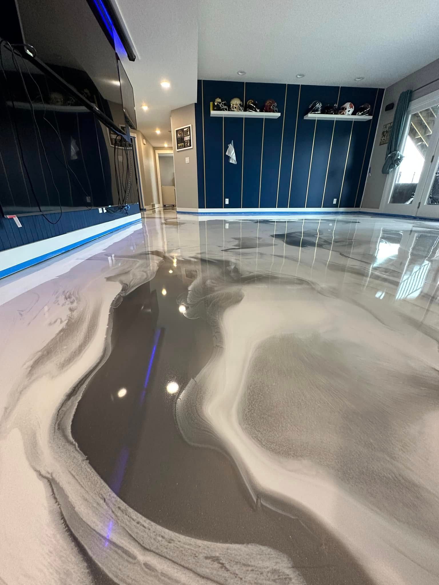 Glossy, marbled gray epoxy floor reflecting light in a room with blue accents and a dark entertainment unit.