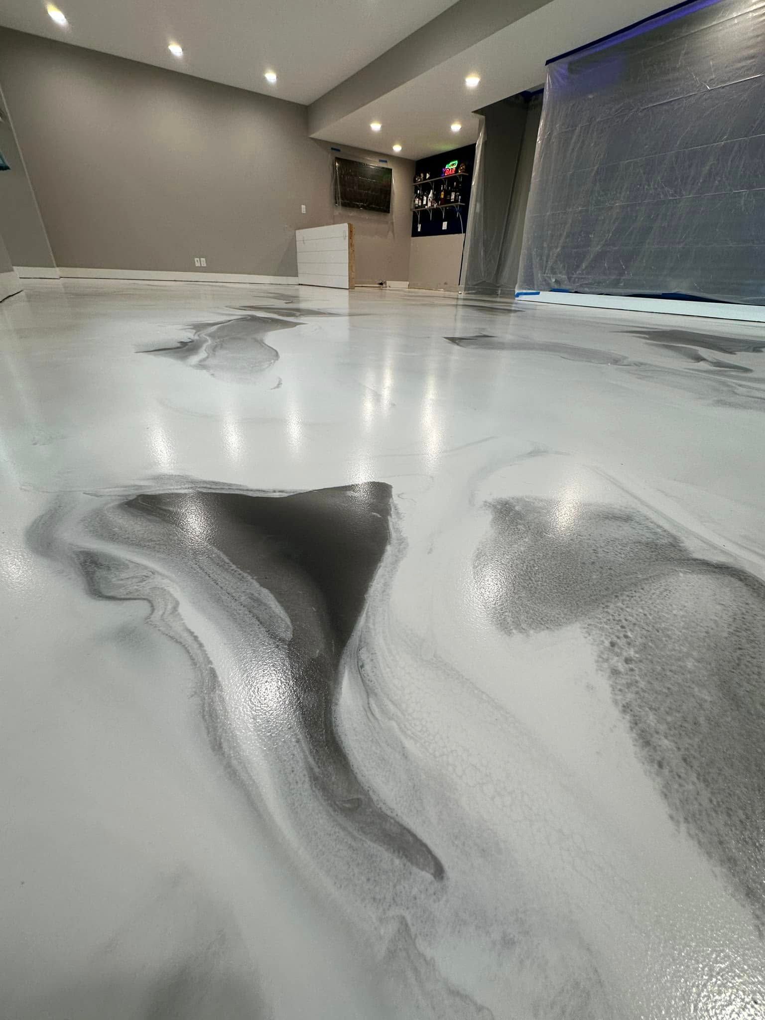 Metallic epoxy floor in swirls of white and gray, reflecting overhead lights.