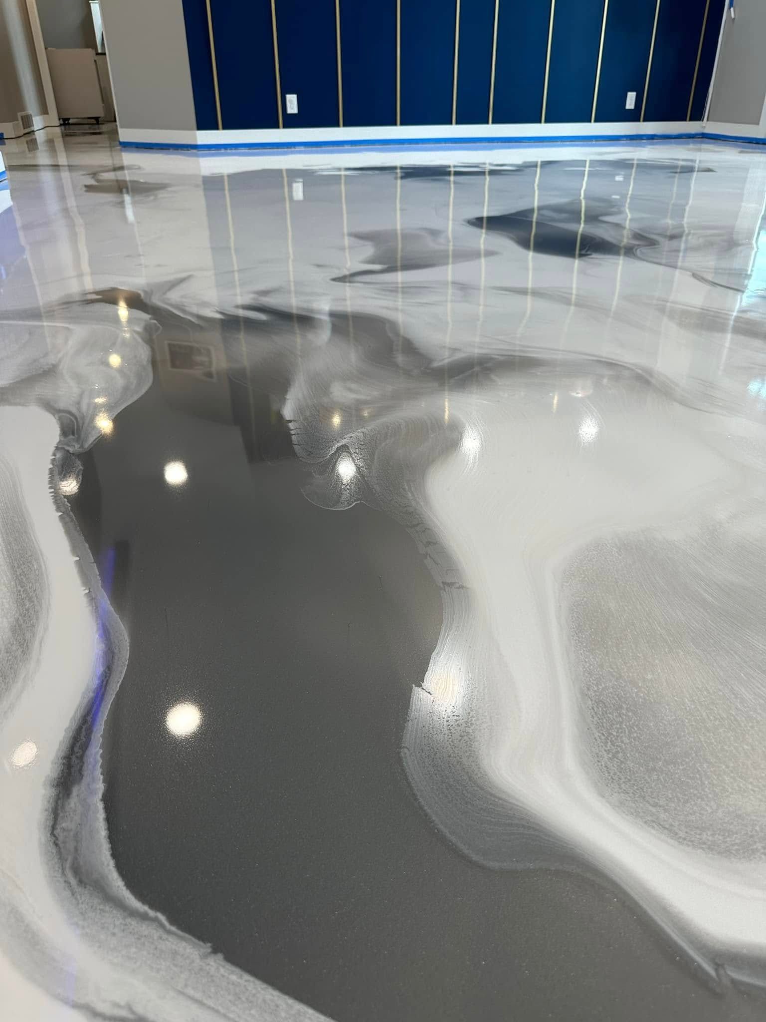 Metallic epoxy flooring in shades of gray and white, with a glossy, swirled design.
