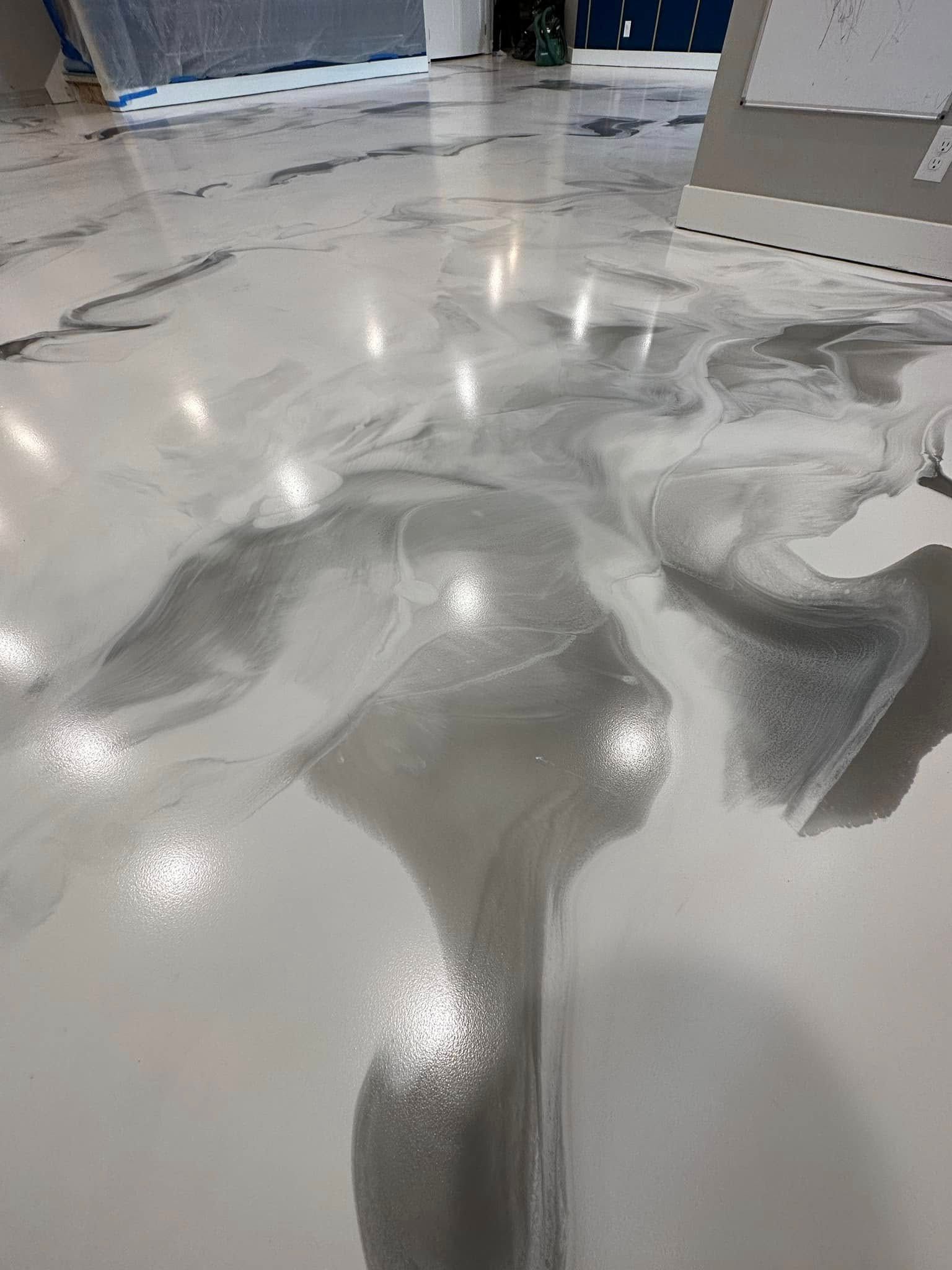 Glossy, swirled silver and white epoxy flooring reflecting overhead lights.