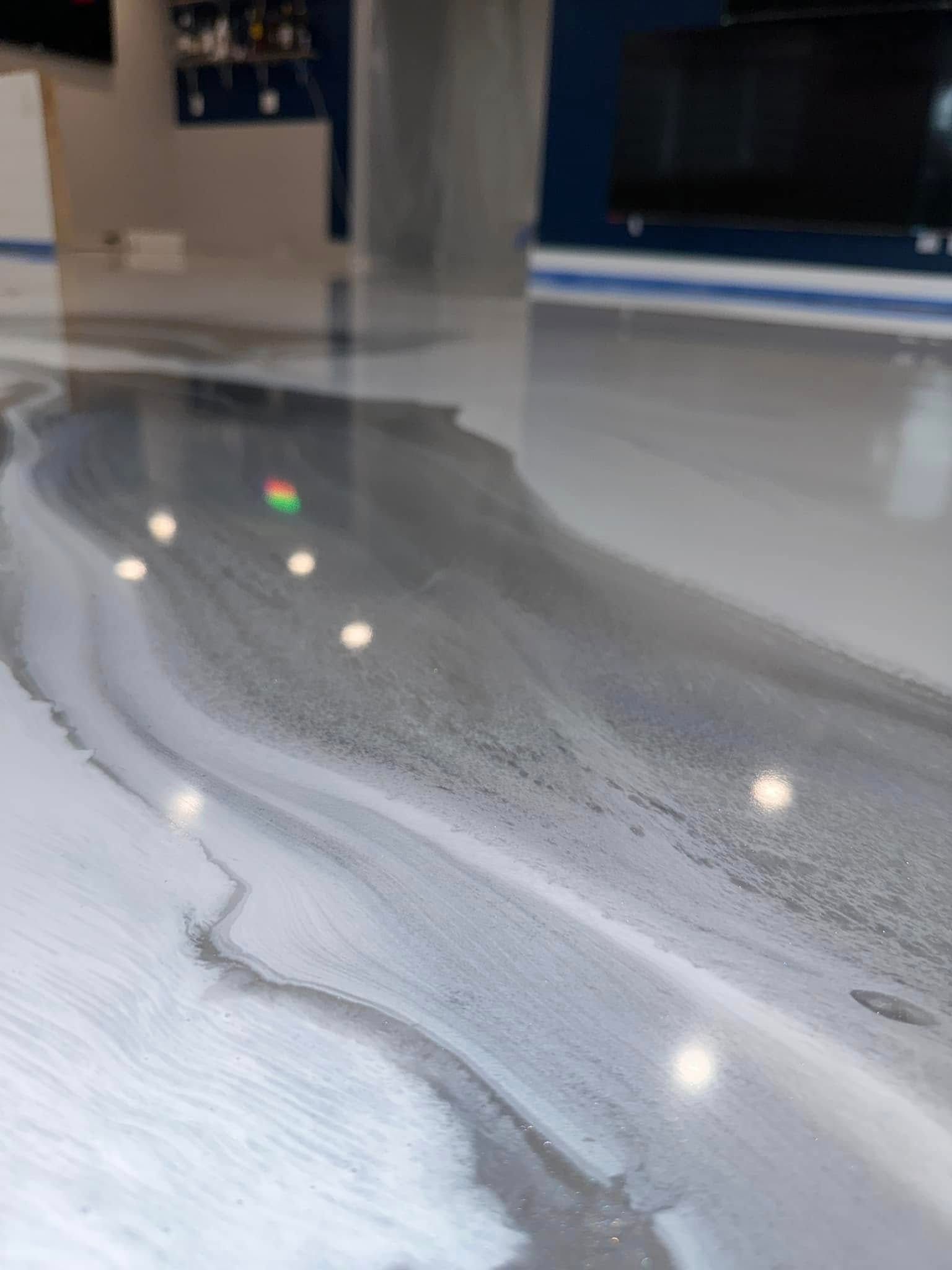 Metallic epoxy floor with gray and white flowing design.
