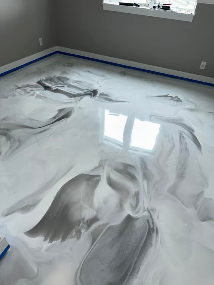 Swirled metallic epoxy floor in shades of gray and white, reflecting light from a window.