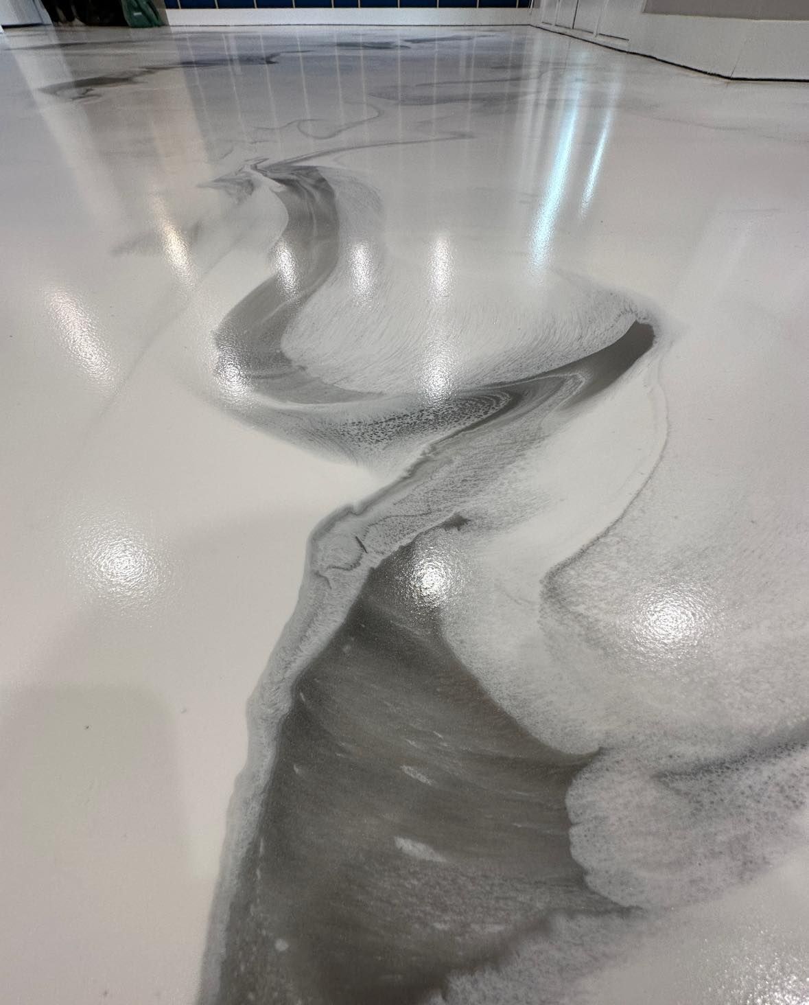 Glossy white and gray epoxy floor with flowing, marbled design.
