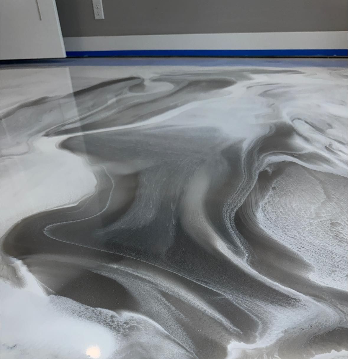 Metallic epoxy floor with swirls of gray and white.