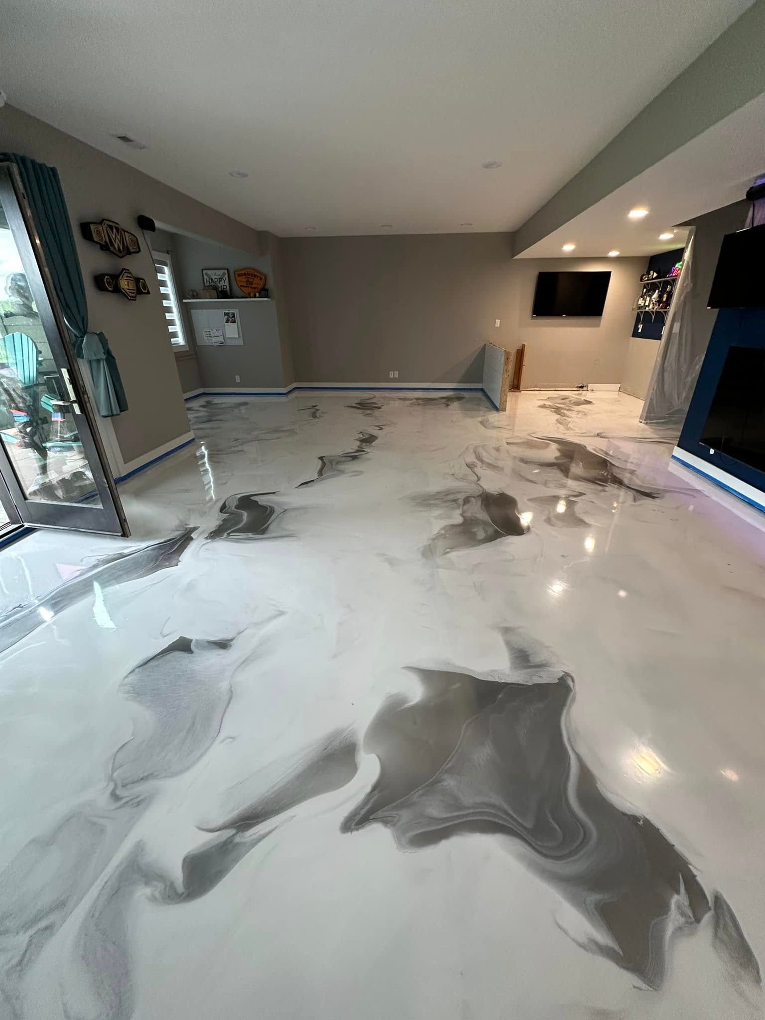 A room with a white and gray epoxy floor. Window and television visible.