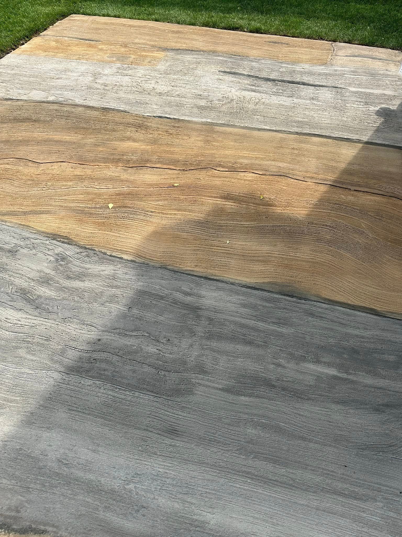 Multi-toned stone patio with green grass border.