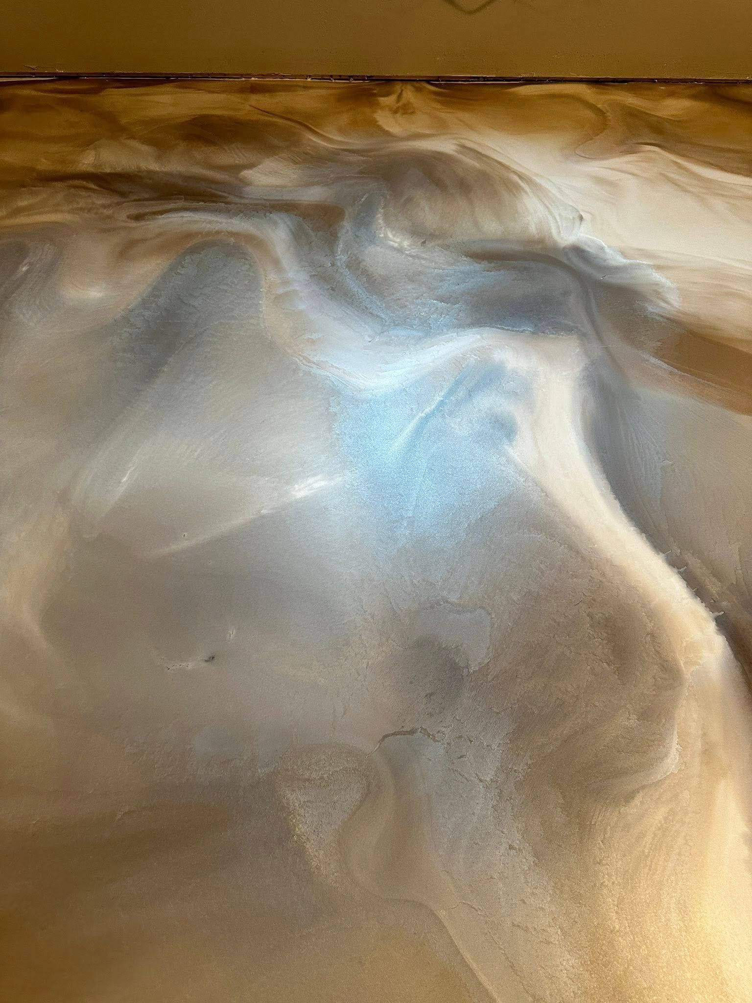 Metallic epoxy flooring with swirling silver, brown, and blue tones.