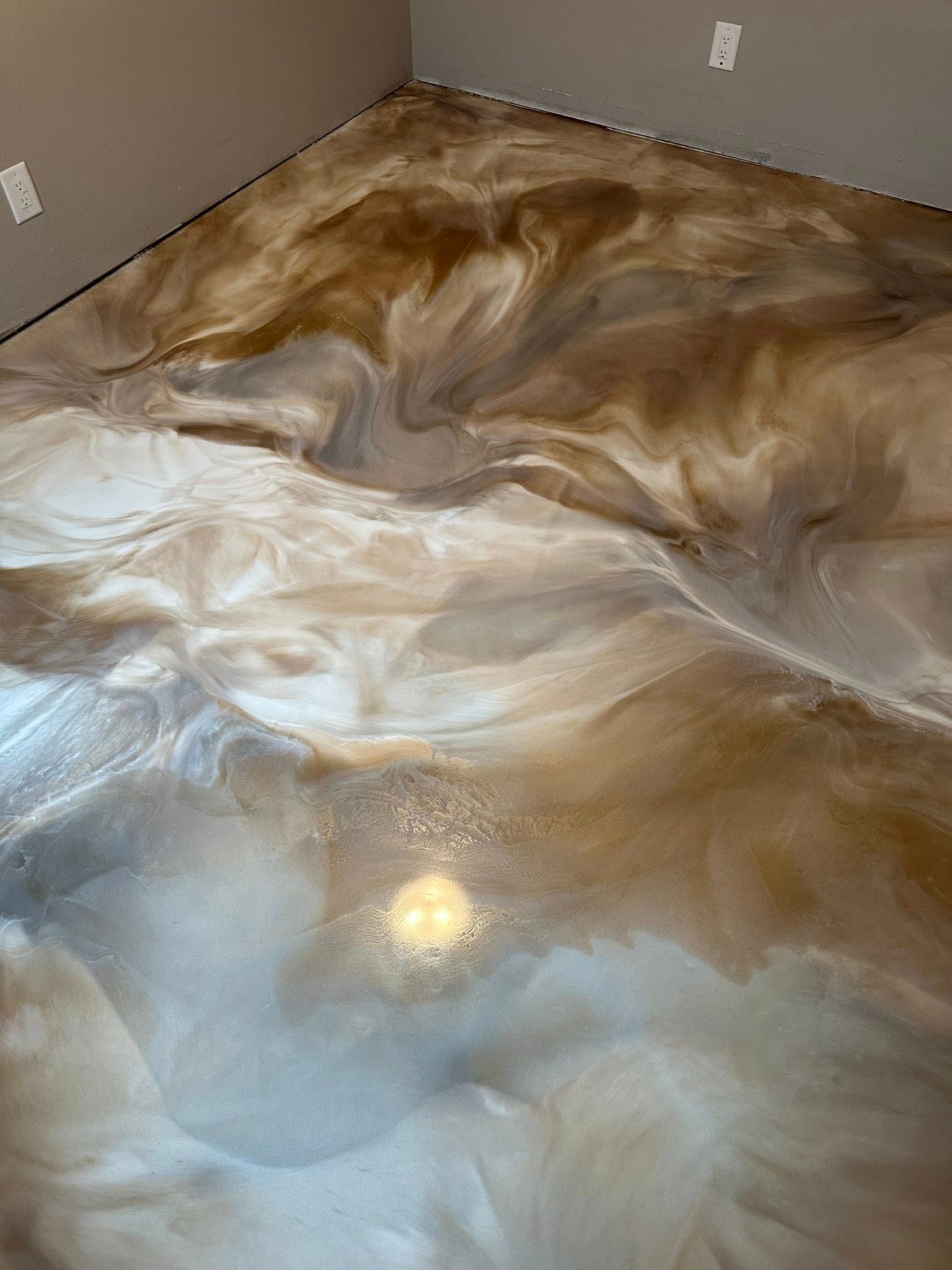 Metallic epoxy floor in shades of gold and silver with a swirled pattern.