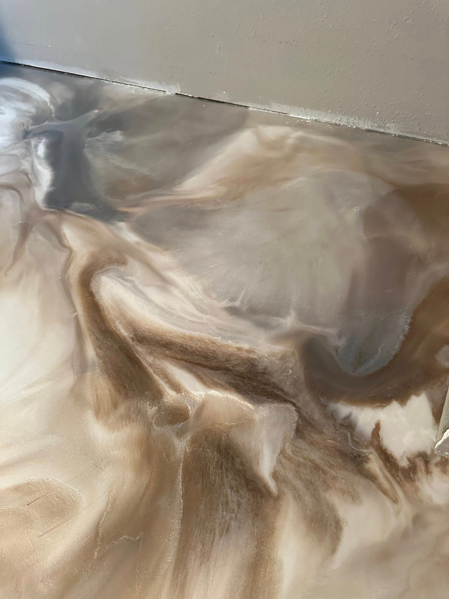 Metallic epoxy floor with swirled beige, brown, and gray patterns.